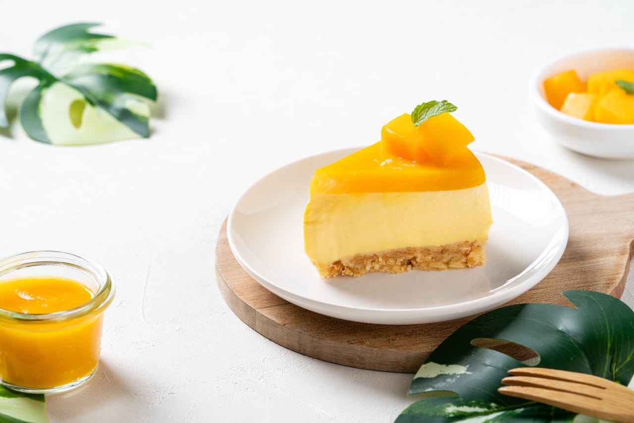 Related image delicious glazed mango no baked cheese cake with fresh diced mango pulp topping bright table background