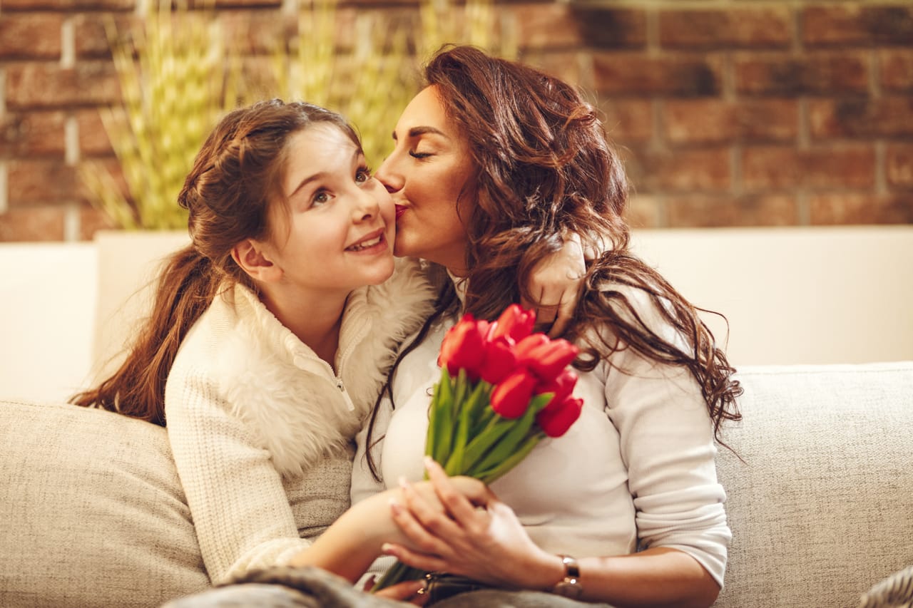 Related image amazed cheerful charming mum is holding nice flowers is giving kiss daughter who is congratulating mothers day her